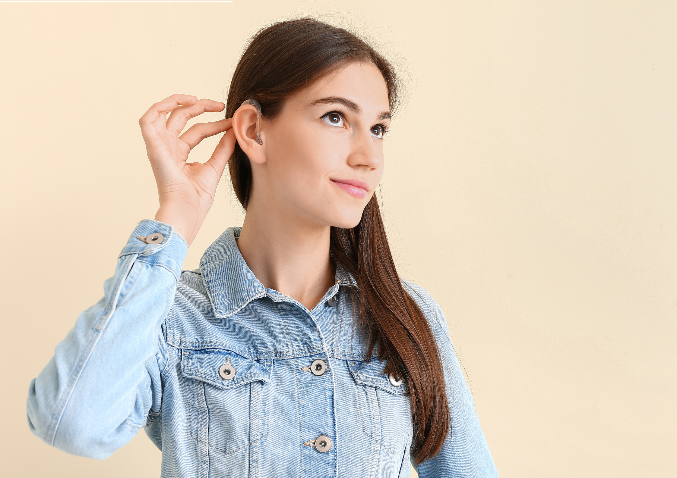 Young woman adjusting a small, discreet hearing aid, showcasing comfort and ease of use.