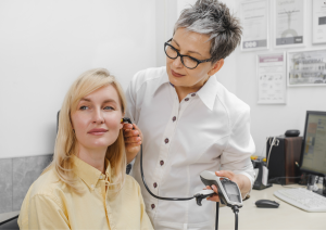 Experienced audiologist providing personalized fitting and adjustment of a woman's hearing aid.